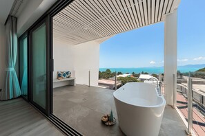 A modern bathroom with a large bathtub, a bench, and a view of the ocean. - Master Peak H4 - 2BR Villa at Bang Rak Beach (Bo phut)
