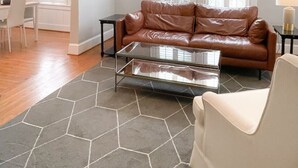 Ein Wohnzimmer mit braunem Ledersofa, einem Glastisch und einem Deckenventilator.