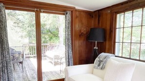 Ein Zimmer mit einer weißen Couch, einem kleinen Tisch mit Tablett, einer Lampe und Blick auf eine Terrasse.