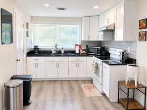 A modern kitchen with white cabinets, a black countertop, and stainless steel appliances.