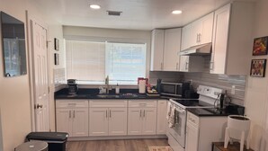 A modern kitchen with white cabinets, a stainless steel sink, and a microwave.