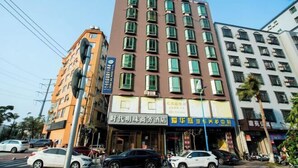 Un immeuble à plusieurs étages abritant divers commerces au rez-de-chaussée, notamment un hôtel et un centre de services automobiles.