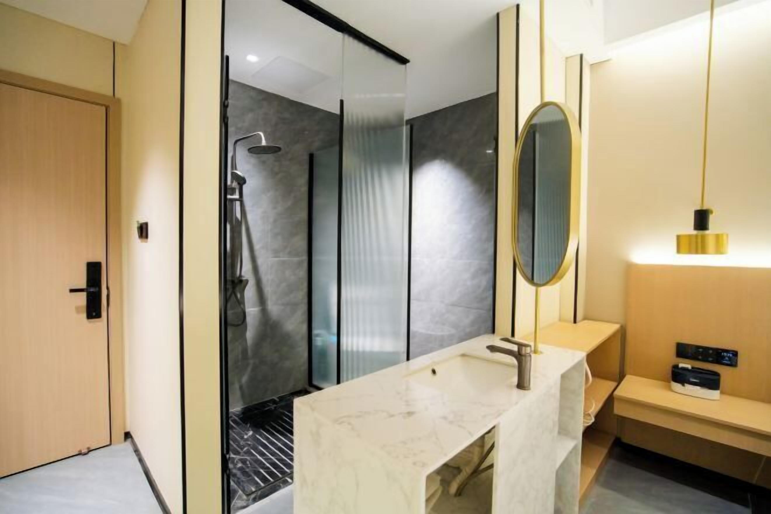 A modern bathroom with a glass shower enclosure, a marble sink, and a mirror with a gold frame.