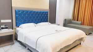 Une chambre d’hôtel comprenant un lit, une table de chevet, un coin salon et un rideau.