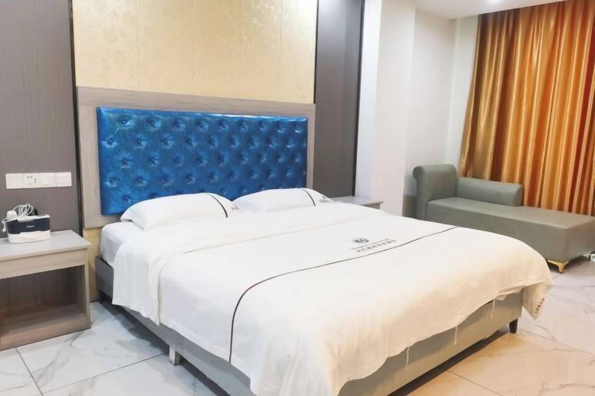 Ein Hotelzimmer mit Bett, Nachttisch, Sitzecke und Vorhang.