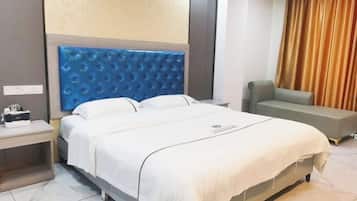A hotel room with a bed, a nightstand, a seating area, and a curtain.