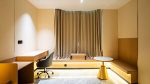 Une chambre d’hôtel moderne équipée d’un bureau, d’une chaise, d’une petite table et d’un banc.