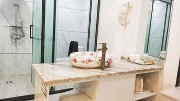 A bathroom with a marble vanity, a shower, and a toilet.