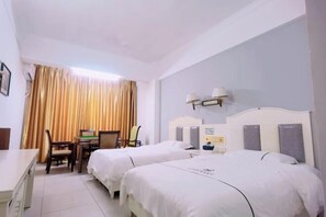 Habitación de hotel con dos camas, un escritorio, sillas y una ventana con cortinas.