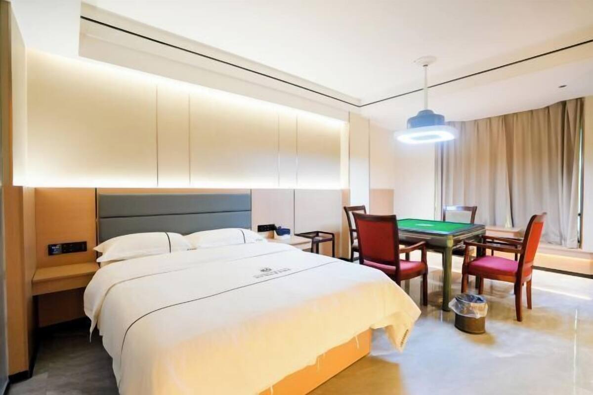 Ein Hotelzimmer mit Bett, Schreibtisch, Stuhl, Tisch und Billardtisch.