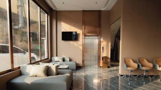 Un hall d’entrée moderne avec un canapé, des fauteuils, un téléviseur et un ascenseur.