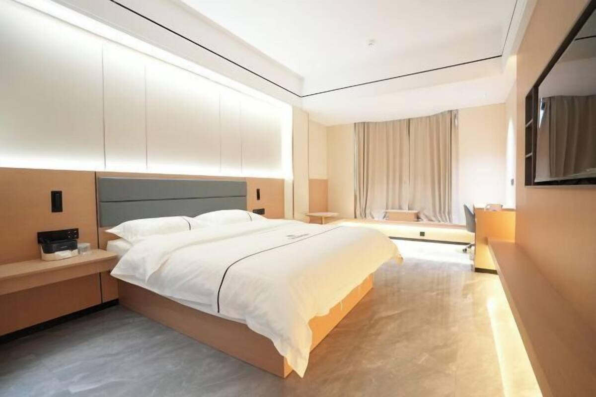 Ein modernes Hotelzimmer mit einem großen Bett, Nachttischen, einem Schreibtisch und einem Stuhl.