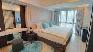 A modern bedroom with a large bed, a bedside table, a mirror, and a television in the background. - Viva Lavida Hotel (Bangkok)