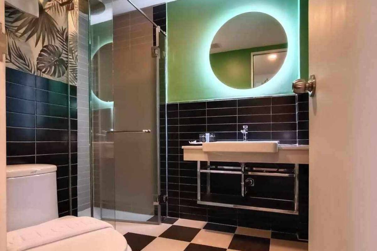 A bathroom with a checkered floor, a toilet, a sink, and a shower.