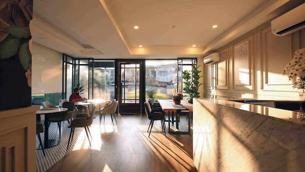 A spacious dining area with a large window, a kitchen area with a counter, and a seating arrangement with chairs and tables. - Viva Lavida Hotel (Bangkok)