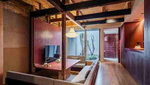 A modern interior with a wooden floor, a seating area with cushions, a table, and a hanging light fixture. - Akeiro Machiya House (Kyoto)