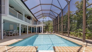 A swimming pool with a covered area, lounge chairs, and a patio with outdoor furniture. - Gorgeous 5 Bedroom Home with Heated Pool and Spa (Sanibel)