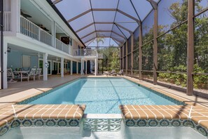 A swimming pool with a covered area, lounge chairs, and a patio with outdoor furniture.