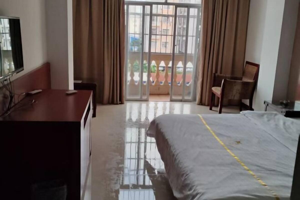 A hotel room with a bed, a desk, a chair, and a TV.