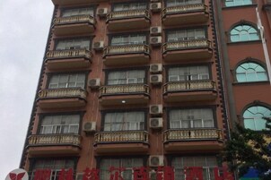 Un edificio de varios pisos con balcones, unidades de aire acondicionado y un letrero rojo en la parte inferior.