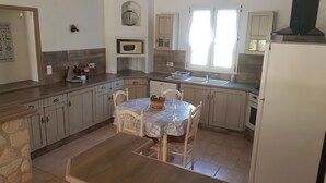 Una cocina con una mesa de comedor, sillas, microondas, lavabo y armarios.