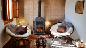 A cozy room with two cushioned chairs, a wood-burning stove, and a small table. - Casa Paradis - Callosa d'En Sarria, Costa Blanca (Callosa d'En Sarria)