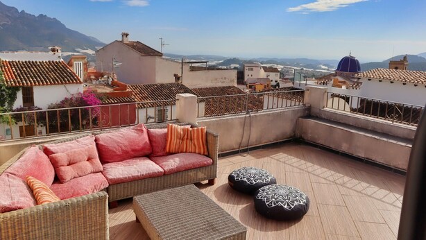 A rooftop terrace with a wicker sofa, two ottomans, and a view of the city and mountains. - Casa Paradis - Callosa d'En Sarria, Costa Blanca (Callosa d'En Sarria)