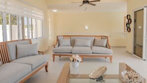 A modern living room with a sofa, a glass coffee table, and a ceiling fan. - Paradise Island  (Sosúa)