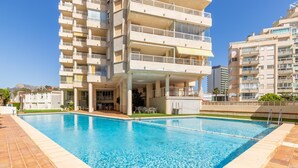 A swimming pool surrounded by multi-story residential buildings with balconies and outdoor seating areas. - Piso Aqua Park by Solidays - Calpe, Costa Blanca (Calpe)