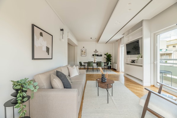 A modern living room with a sofa, a coffee table, and a dining area with chairs and a table.