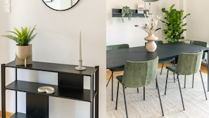 Uma sala de jantar moderna com uma mesa preta, cadeiras verdes e uma grande planta em vaso.