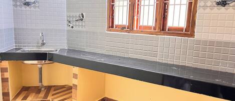 Una cocina con encimera negra, un fregadero y una ventana con contraventanas de madera.