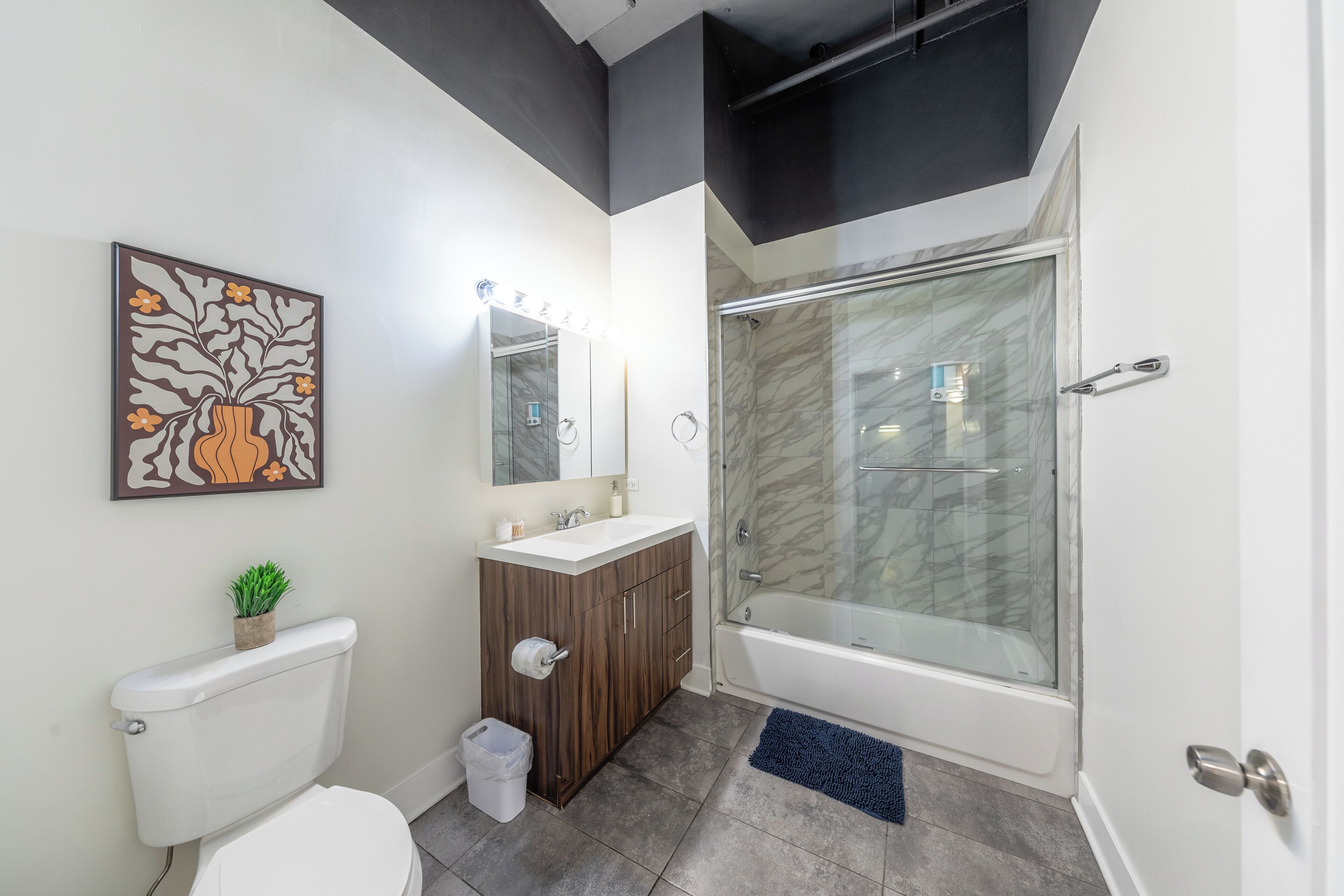 A bathroom with a toilet, sink, vanity, and a glass-enclosed shower.