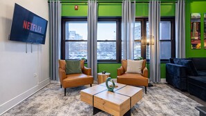 Un espace détente moderne avec des fauteuils en cuir, une table basse en bois et un grand téléviseur à écran plat affichant le logo de Netflix.