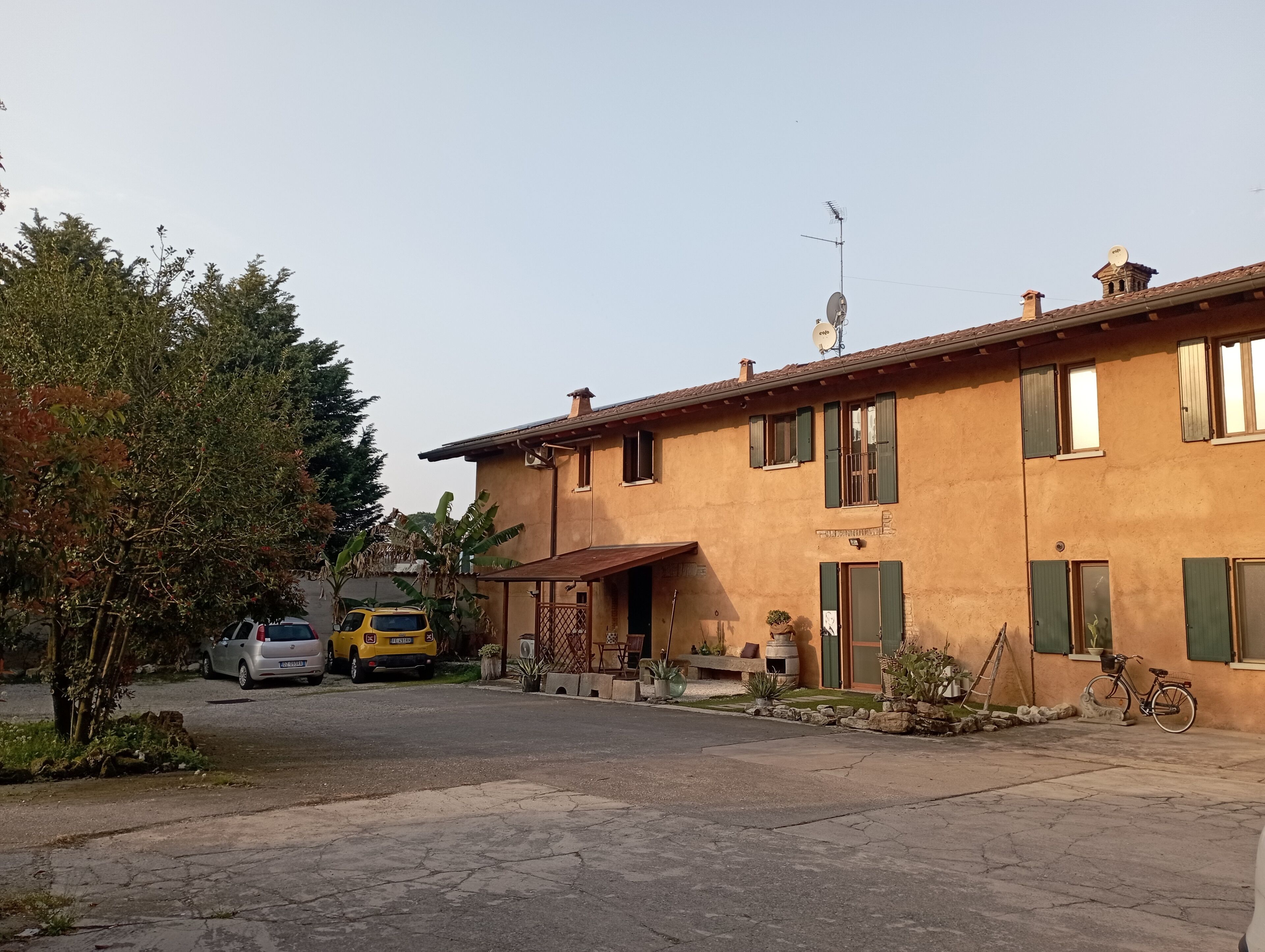 Edifici de dues plantes amb façana rústica, una antena parabòlica i una bicicleta aparcada a l'exterior.