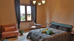 A bedroom with a bed, a sofa, a small table, and a chair.