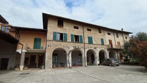 A two-story building with a courtyard, featuring arched doorways and a car parked in front.