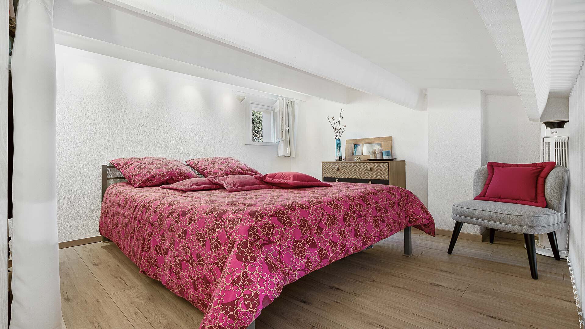 Une chambre à coucher avec un lit, une chaise, une commode et un radiateur.