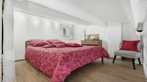 A bedroom with a bed, a chair, a dresser, and a radiator. - Bright apt for 4 ppl, balcony, private parking (Agde)