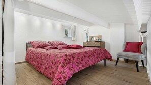 A bedroom with a bed, a chair, a dresser, and a radiator.