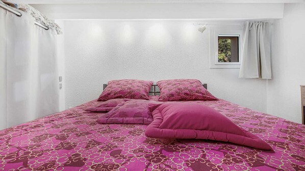 Une chambre à coucher avec un lit, des oreillers et une fenêtre.