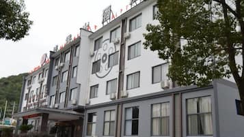 A multi-story hotel with a modern design, featuring a prominent logo on the facade, large windows, and a flat roof.