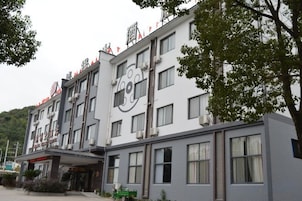 Un hotel de varios pisos con un diseño moderno, que presenta un logotipo destacado en la fachada, ventanas amplias y un techo plano.