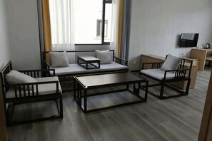 A modern living room with a sofa set, a coffee table, and a TV mounted on the wall.