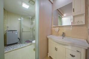 A bathroom with a glass shower enclosure, a white sink, and a mirror above the sink. - Hong Xiang Hotel (Xiangshan)