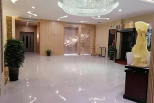 Un vestíbulo de hotel con piso pulido, una araña y una mesa de recepción.