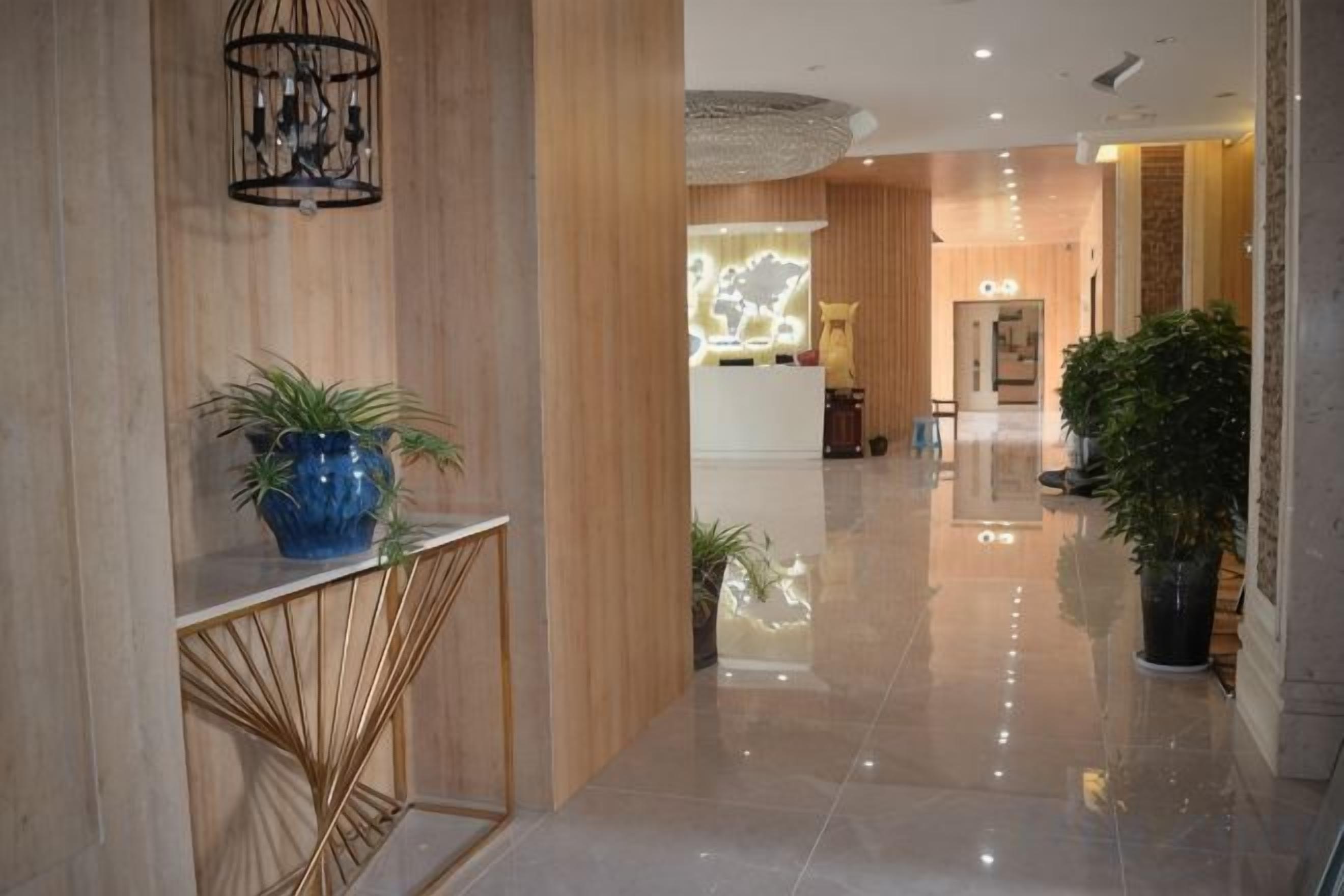 A hotel lobby with a reception desk, a reception area, and a large potted plant.