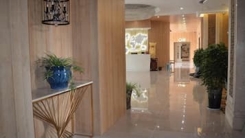 A hotel lobby with a reception desk, a reception area, and a large potted plant.