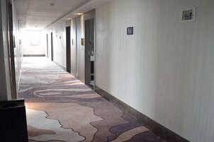 Un pasillo de hotel con alfombra estampada, puertas y una lámpara.
