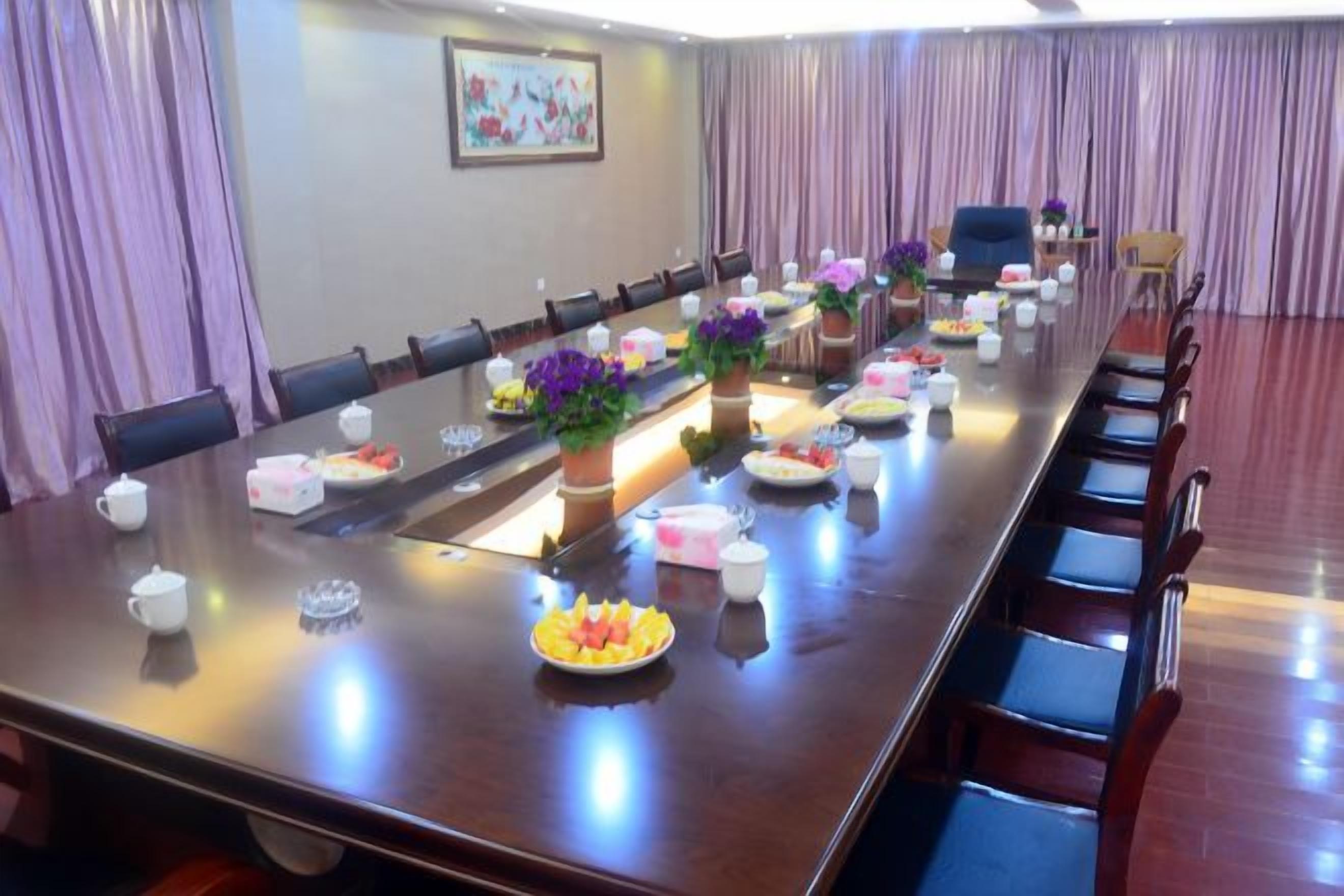 A conference room with a long table, chairs, and floral centerpieces.
